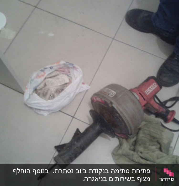 כלי עבודה של אינסטלטור על רצפה, כולל מקדחה וחוטים